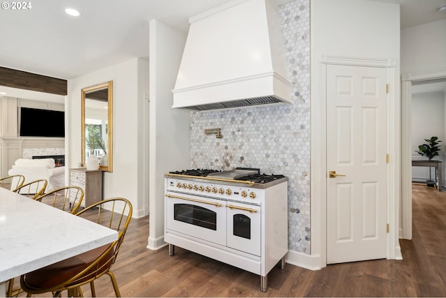 kitchen with white cabinetry, premium range hood, dark hardwood / wood-style floors, range with two ovens, and decorative backsplash