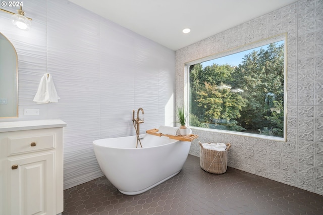 bathroom featuring tile patterned floors, tile walls, a tub to relax in, and vanity