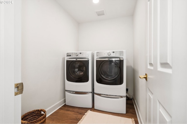 clothes washing area with dark hardwood / wood-style floors and washing machine and dryer