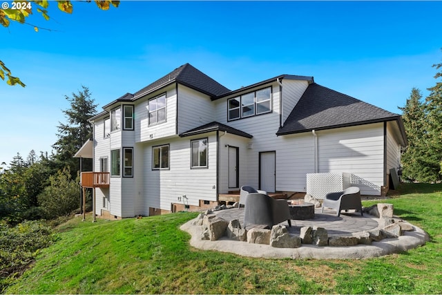 rear view of house with a fire pit, a lawn, and a patio