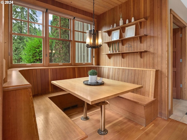 dining space with breakfast area, wooden ceiling, light hardwood / wood-style floors, an inviting chandelier, and wood walls