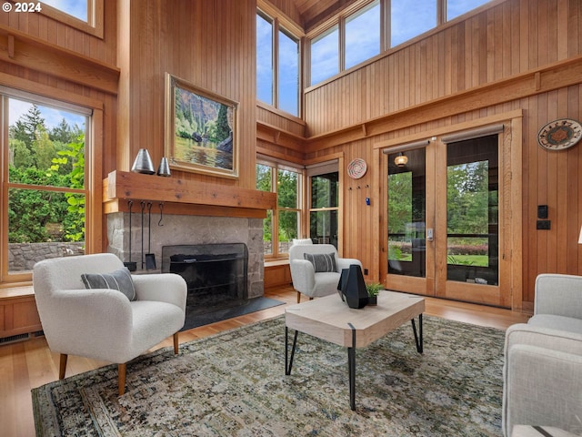 living room with a high ceiling, wooden walls, and a healthy amount of sunlight