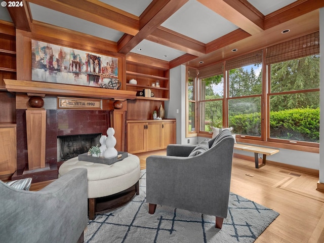 living room with coffered ceiling, beamed ceiling, light wood-type flooring, and a tiled fireplace