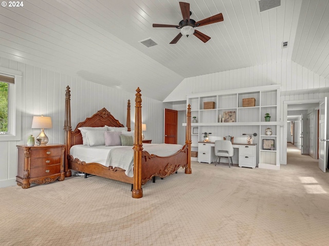 carpeted bedroom with built in desk, vaulted ceiling, wooden walls, and ceiling fan