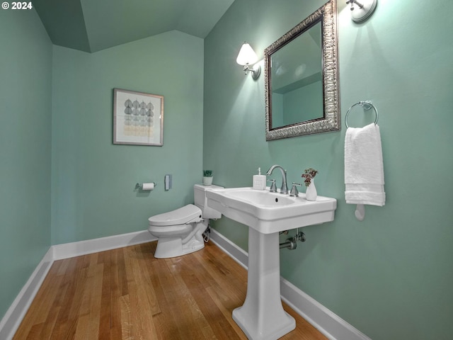 half bath with toilet, baseboards, wood finished floors, and lofted ceiling