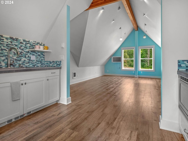 additional living space with sink, lofted ceiling with beams, and light hardwood / wood-style floors