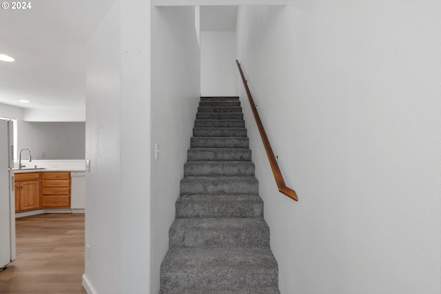 staircase featuring hardwood / wood-style flooring and sink