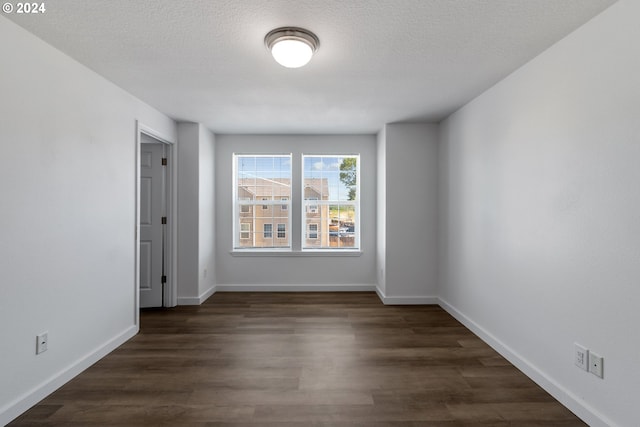 empty room with dark hardwood / wood-style flooring and a textured ceiling