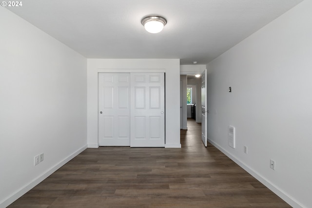 unfurnished bedroom featuring dark hardwood / wood-style flooring and a closet