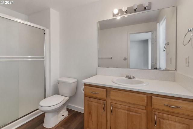 bathroom with vanity, hardwood / wood-style flooring, a shower with shower door, and toilet