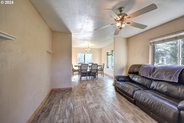 living room featuring hardwood / wood-style floors, a textured ceiling, and ceiling fan with notable chandelier