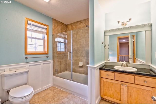 full bathroom with a textured ceiling, bath / shower combo with glass door, toilet, and vanity