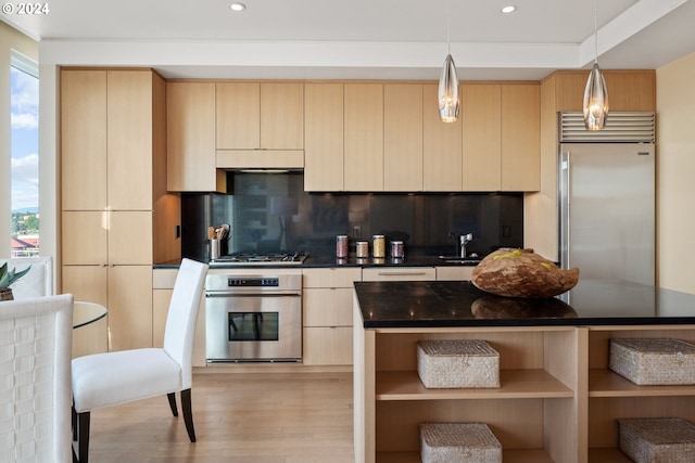 kitchen with pendant lighting, appliances with stainless steel finishes, a wealth of natural light, tasteful backsplash, and light brown cabinetry