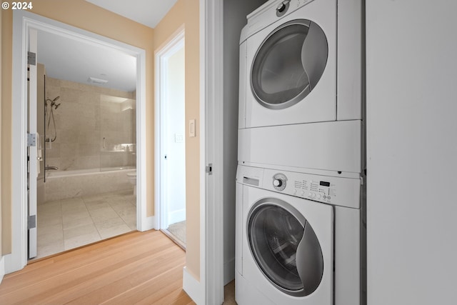 clothes washing area with stacked washer and dryer and hardwood / wood-style floors