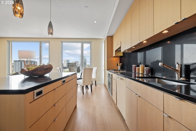 kitchen featuring pendant lighting, sink, light brown cabinets, and backsplash