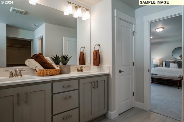 bathroom with double vanity, connected bathroom, visible vents, and a sink