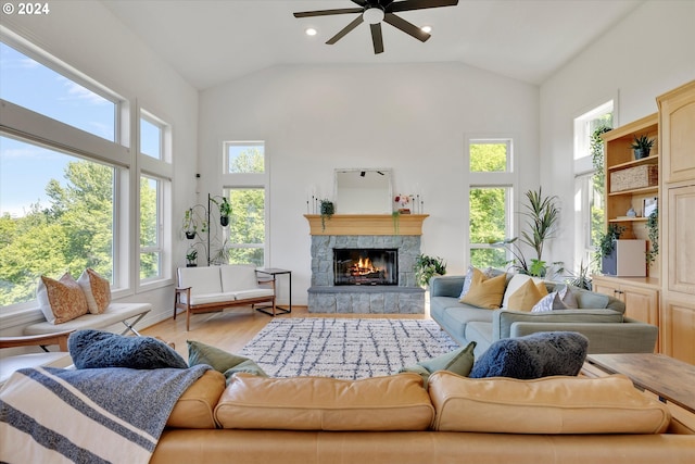 living room featuring ceiling fan, high vaulted ceiling, light wood-type flooring, and a fireplace