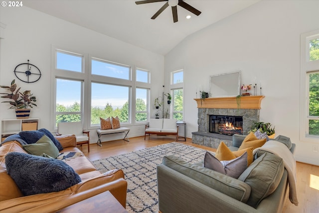 living room featuring light hardwood / wood-style floors, a fireplace, ceiling fan, and high vaulted ceiling