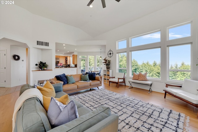 living room featuring light wood-type flooring, ceiling fan, and vaulted ceiling