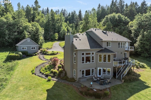 rear view of property with a patio, an outbuilding, a lawn, and a wooden deck