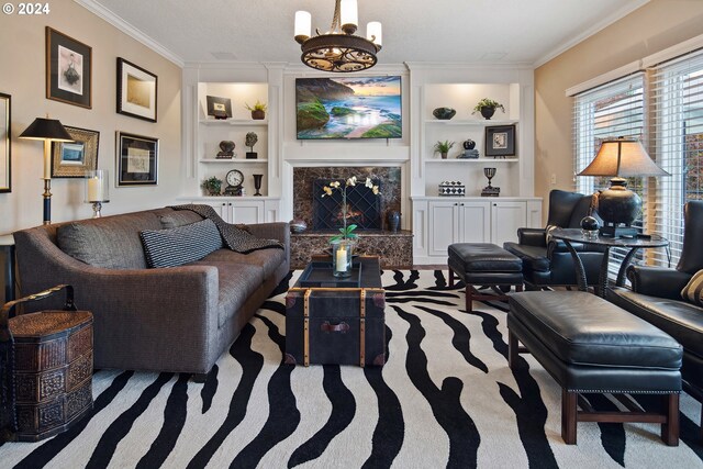 living room featuring an inviting chandelier, crown molding, a fireplace, and built in shelves