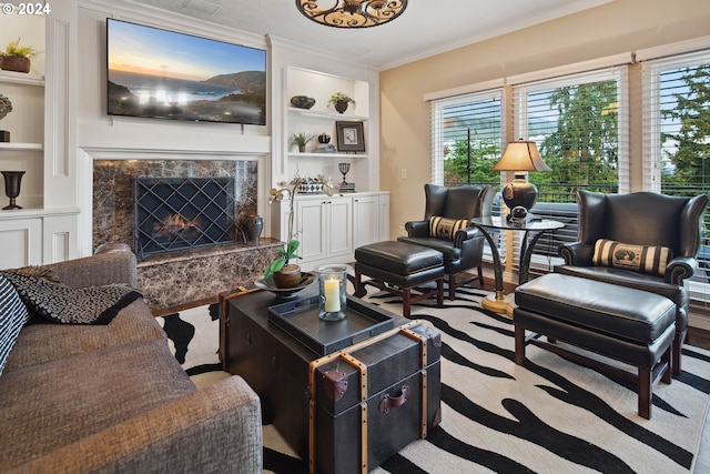 living room with crown molding, a premium fireplace, and built in features