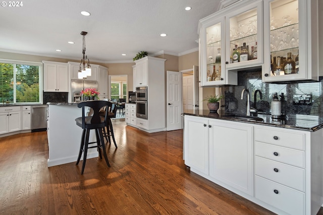 kitchen featuring sink, hanging light fixtures, a kitchen island, stainless steel appliances, and white cabinets