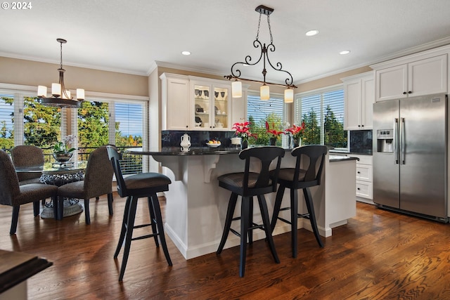 kitchen featuring decorative light fixtures, white cabinets, a kitchen breakfast bar, and stainless steel fridge with ice dispenser