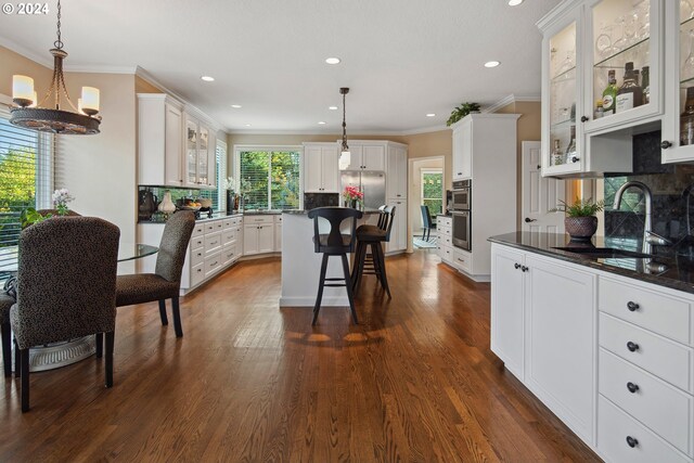 kitchen with stainless steel appliances, a kitchen breakfast bar, hanging light fixtures, and white cabinets