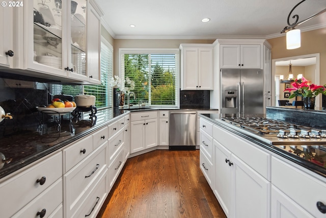 kitchen featuring sink, white cabinets, dark hardwood / wood-style flooring, ornamental molding, and stainless steel appliances