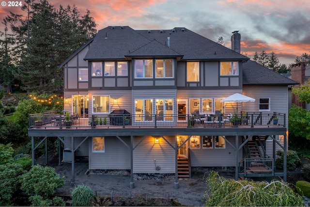 back house at dusk featuring a wooden deck