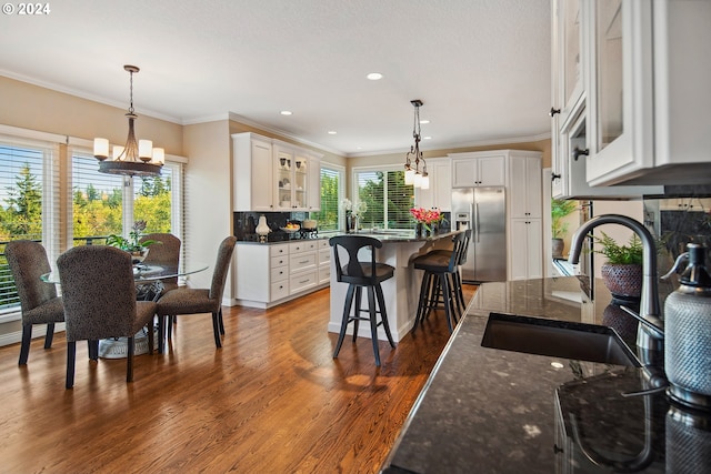 kitchen featuring white cabinetry, stainless steel refrigerator with ice dispenser, sink, and a kitchen breakfast bar