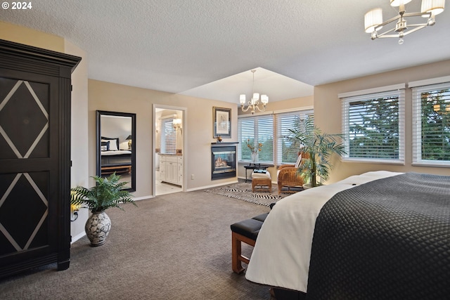 bedroom featuring carpet floors, a textured ceiling, a chandelier, and ensuite bath