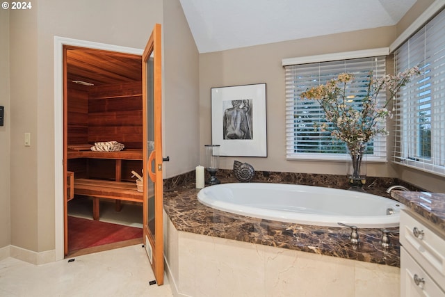 bathroom with vaulted ceiling, tiled bath, and vanity