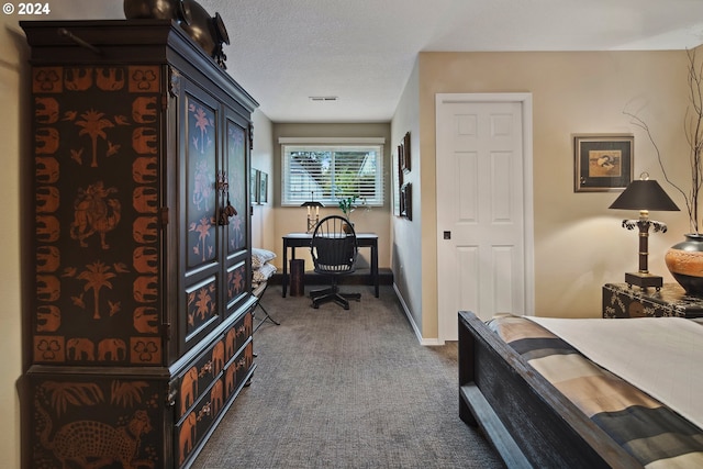 bedroom with a textured ceiling and dark colored carpet