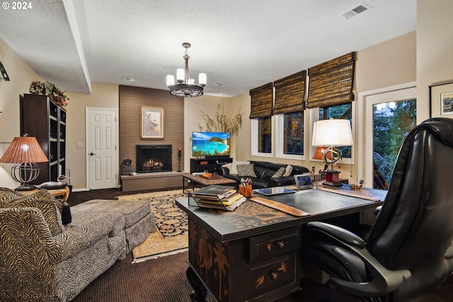 office featuring an inviting chandelier, carpet flooring, a brick fireplace, and a textured ceiling