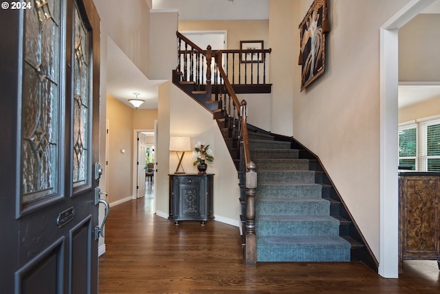 foyer with a towering ceiling and dark wood-type flooring