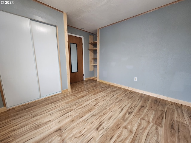 unfurnished bedroom featuring a closet, light hardwood / wood-style flooring, and crown molding