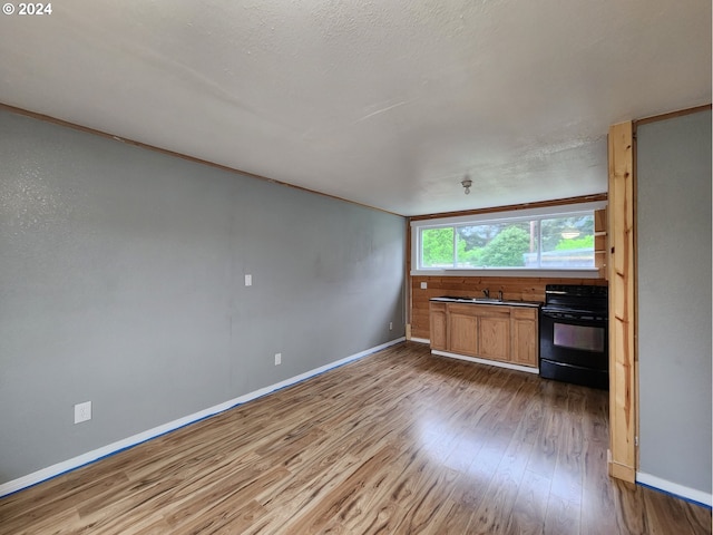 kitchen featuring wood-type flooring, a textured ceiling, crown molding, and black range with electric stovetop