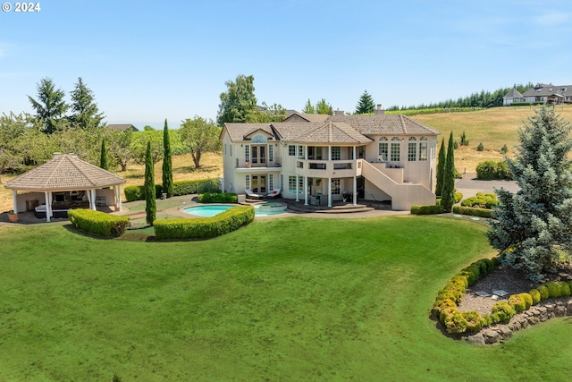 back of property with a balcony, a lawn, a patio area, and a gazebo