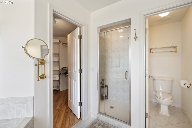 bathroom with toilet, tile patterned flooring, and a shower with shower door