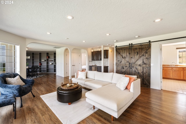 living room featuring sink, dark hardwood / wood-style flooring, a textured ceiling, and a barn door