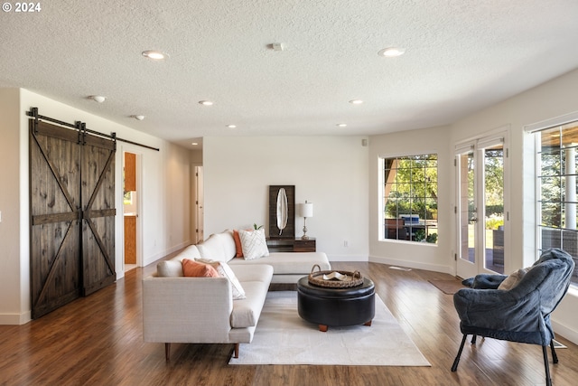 living room featuring a textured ceiling, a barn door, and hardwood / wood-style flooring