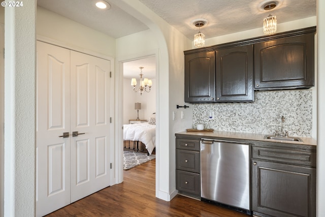 kitchen featuring dark wood-type flooring, stainless steel dishwasher, decorative light fixtures, backsplash, and sink