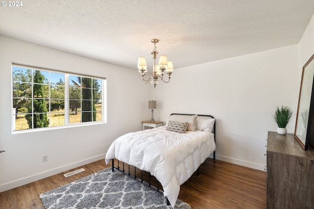 bedroom featuring a textured ceiling, a notable chandelier, and dark hardwood / wood-style floors