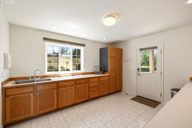 kitchen with sink, a textured ceiling, and light tile patterned floors