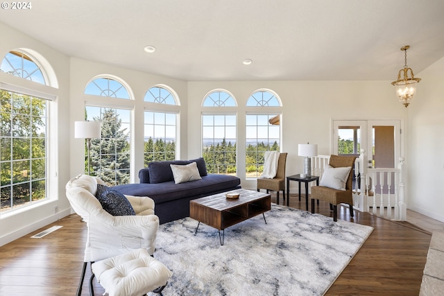 living room with a healthy amount of sunlight, dark hardwood / wood-style flooring, and a chandelier