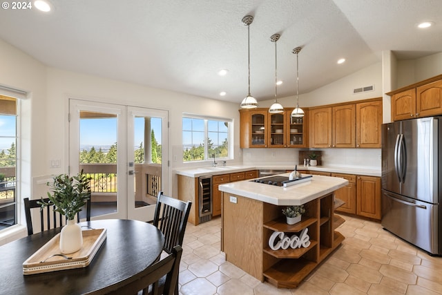 kitchen with beverage cooler, stainless steel refrigerator, hanging light fixtures, a kitchen island, and decorative backsplash