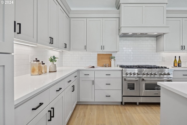 kitchen featuring tasteful backsplash, white cabinetry, and range with two ovens