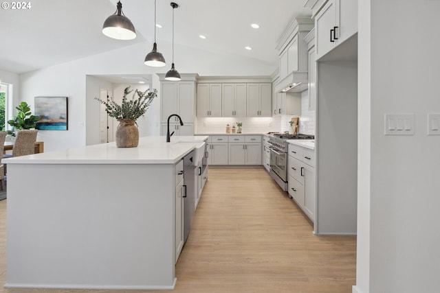 kitchen featuring backsplash, a kitchen island with sink, vaulted ceiling, decorative light fixtures, and stainless steel appliances